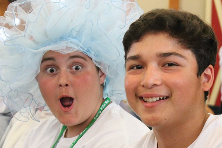 Two boys wearing hats and smiling for the camera.