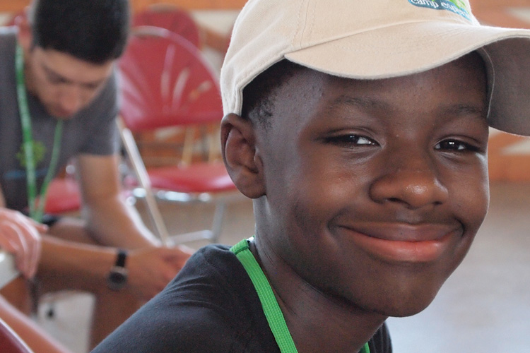 A young boy wearing a white hat and smiling.