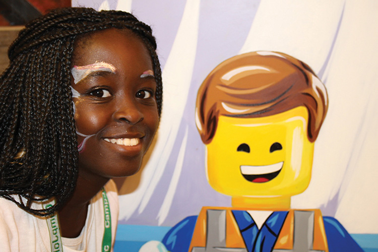 A girl with braids and a lego character on her face.