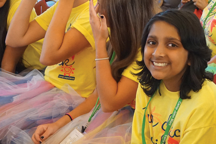 A group of girls wearing yellow shirts and smiling.