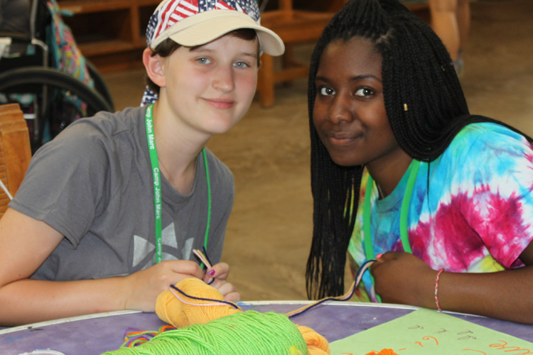 Two people sitting at a table with yarn