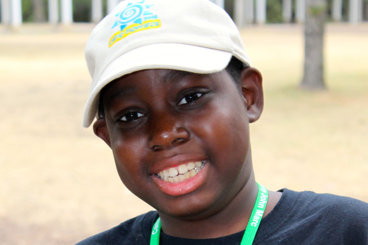 A young boy wearing a hat and smiling.