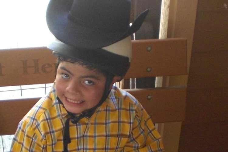 A boy wearing a cowboy hat and smiling.
