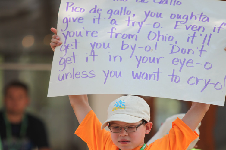 A boy holding up a sign with a message.