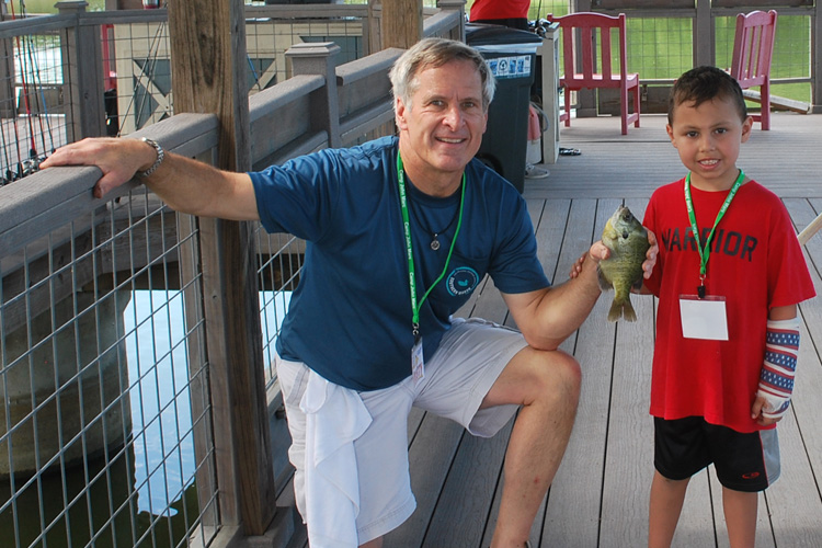 A man and boy holding fish on the deck of a boat.