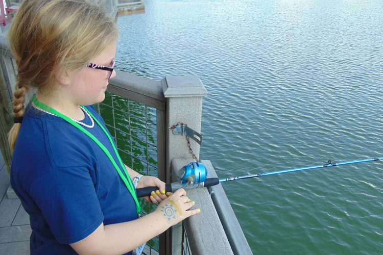 A girl is fishing on the pier.