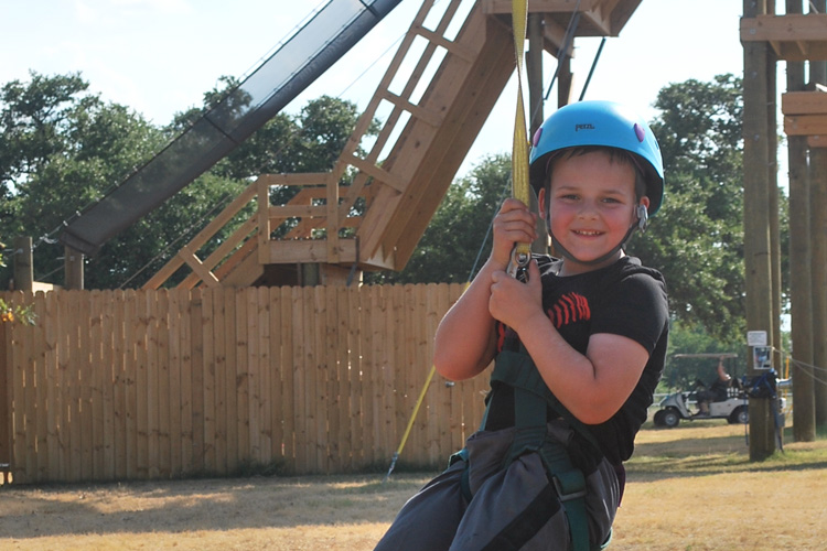 A young boy in a helmet is on a rope.