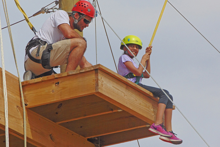 A man and woman on the side of a rope course.