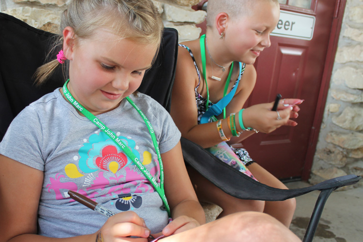 Two girls sitting in a chair with pens and pencils.