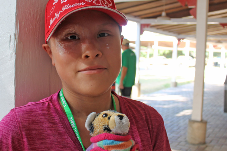 A boy wearing a red hat and holding a stuffed animal.