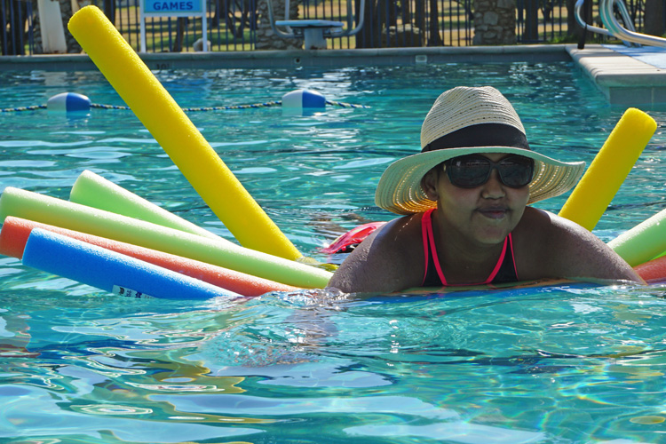 A woman in the pool with several colorful floats.
