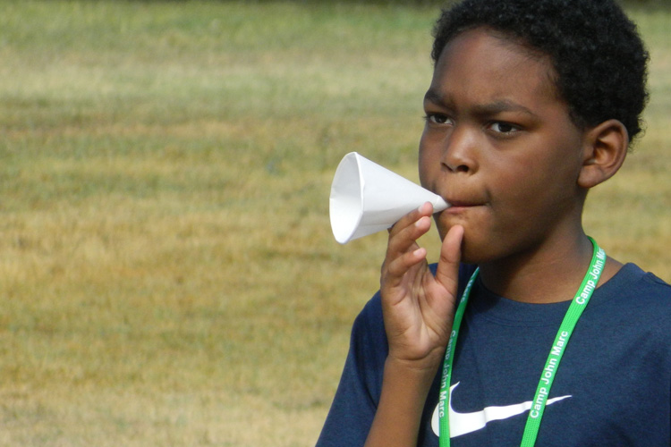 A young boy with a paper cup in his mouth.