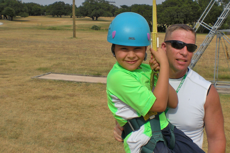 A man and boy with baseball bats in the grass.