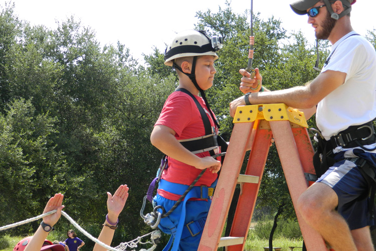 A man is climbing up the ladder of a rope course.