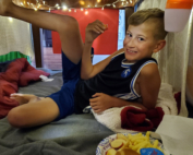 A boy sitting on the floor with his feet up.