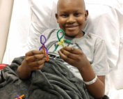 A young boy is holding some colorful scissors.