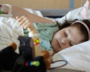 A child laying in bed with toys on the floor.