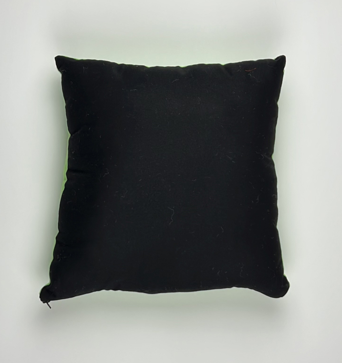 A black pillow on top of a white wall.